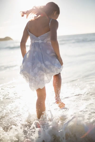 Rear view of gorgeous woman jumping in the waves — Stock Photo, Image