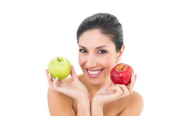 Happy brunette holding red and green apples and looking at camera — Stock Photo, Image