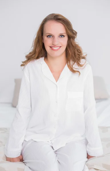 Smiling pretty woman sitting on her bed — Stock Photo, Image