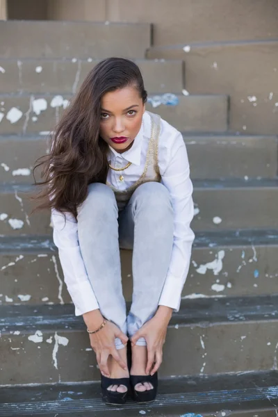 Bonita morena sentada en escaleras tocando sus pies — Foto de Stock