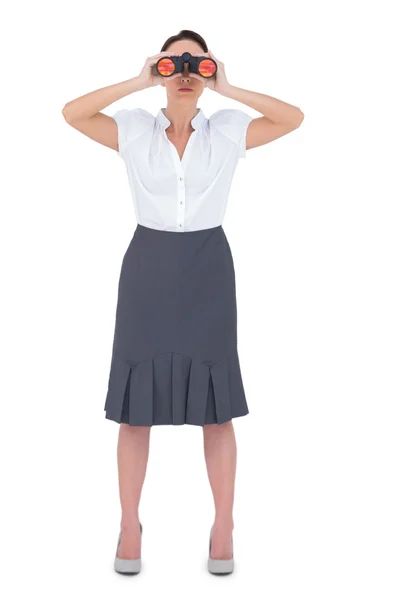 Unsmiling elegant businesswoman looking through binoculars — Stock Photo, Image