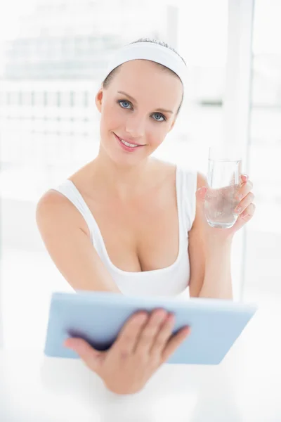 Natürliche hübsche Sportlerin mit einem Glas Wasser und einem Tablet-PC — Stockfoto