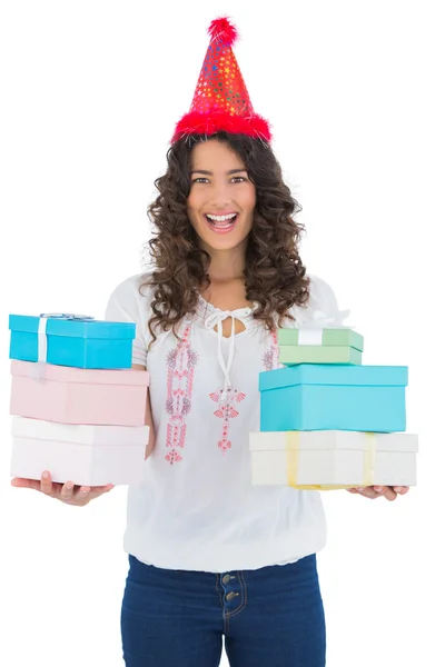 Happy casual brunette wearing party hat holding presents — Stock Photo, Image