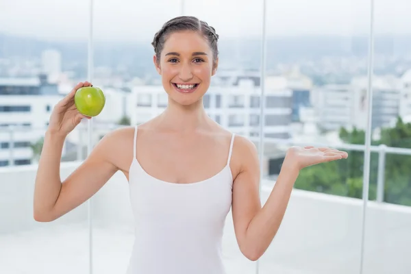 Cheerful sporty brunette holding green healthy apple — Stock Photo, Image