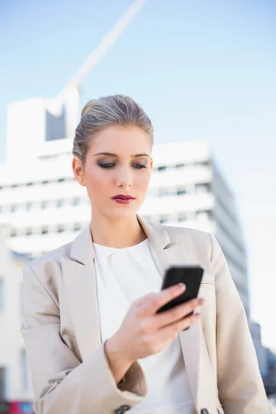Ernsthafte attraktive Geschäftsfrau sendet eine SMS — Stockfoto