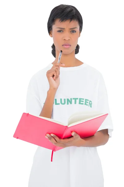 Frowning black haired volunteer holding a notebook — Stock Photo, Image