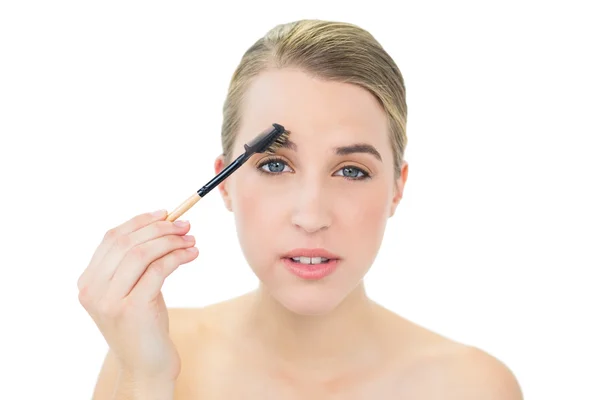 Jolie blonde utilisant une brosse à sourcils — Photo