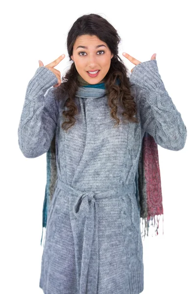 Curly haired model with winter clothes pointing out her head — Stock Photo, Image