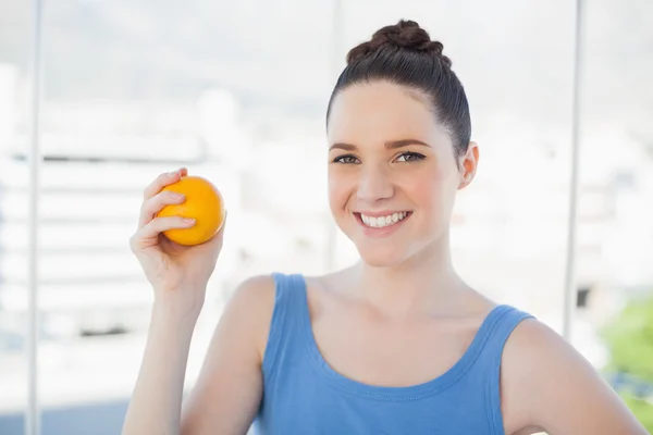 Mujer delgada sonriente en ropa deportiva sosteniendo naranja —  Fotos de Stock