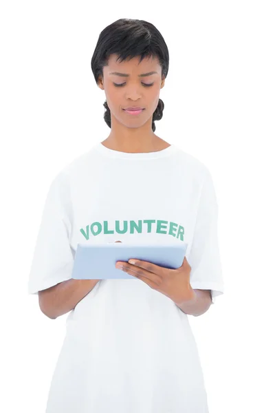 Thoughtful black haired volunteer using a tablet pc — Stock Photo, Image