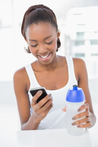Mujer atlética sonriente mirando su teléfono inteligente — Foto de Stock