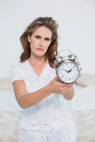 Fronsen moe vrouw toont Wekker — Stockfoto
