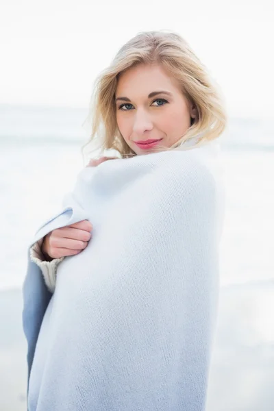 Pleased blonde woman warming herself in a blanket — Stock Photo, Image
