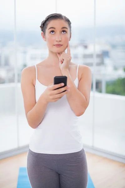 Thoughtful sporty brunette text messaging — Stock Photo, Image