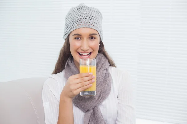 Morena bonita com chapéu de inverno na realização de vidro de suco de laranja — Fotografia de Stock