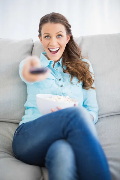 Uśmiechnięta kobieta zmienia kanał tv — Zdjęcie stockowe