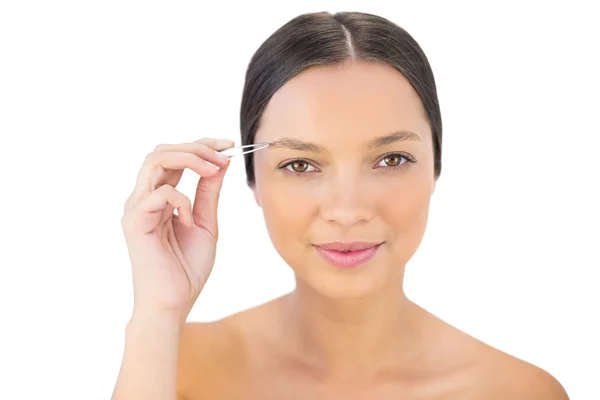 Cheerful natural woman using tweezers for her eyebrow — Stock Photo, Image