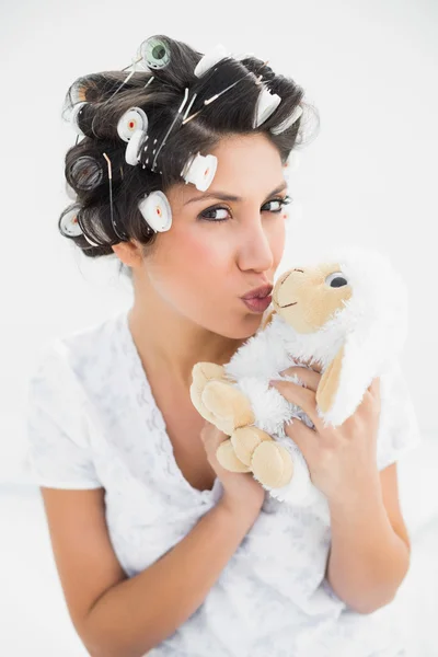 Joyeux brune en rouleaux de cheveux embrassant les moutons en peluche — Photo