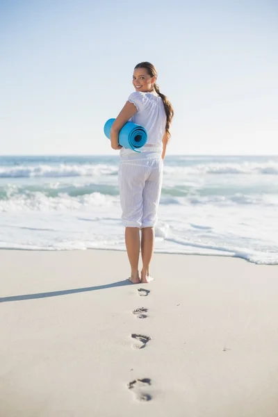 Rear view of gorgeous woman holding exercise mat looking over sh — Stock Photo, Image