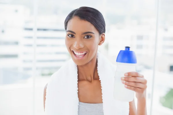 Cheerful sporty model with towel on shoulders holding flask — Stock Photo, Image