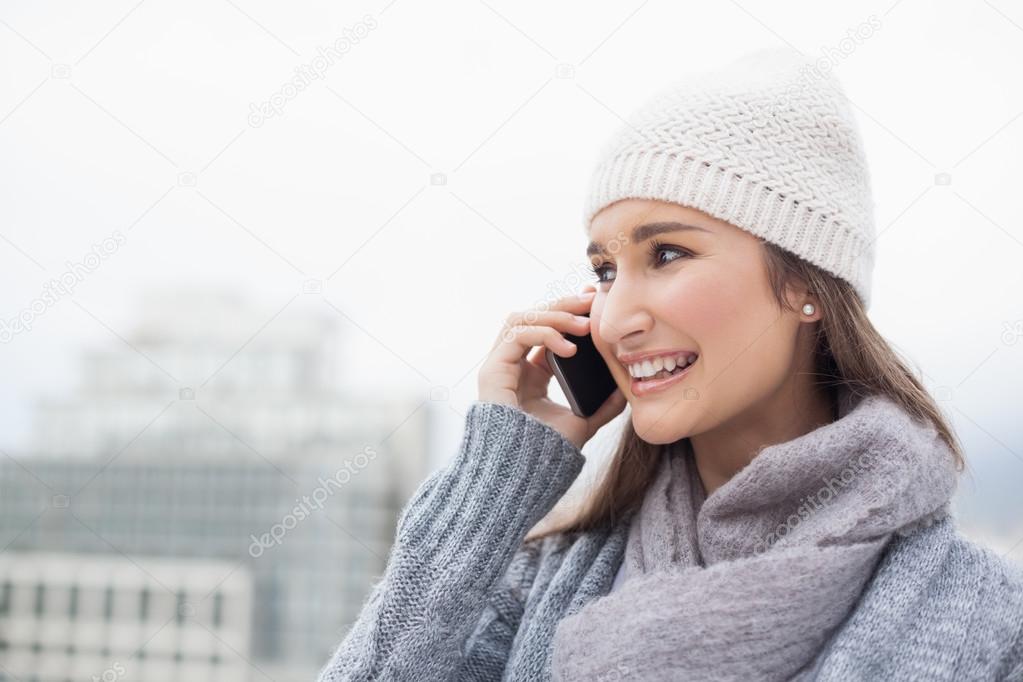 Happy brunette with winter clothes on having a call