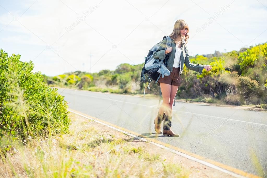 Focus on straw with hitchhiking sexy blonde on background