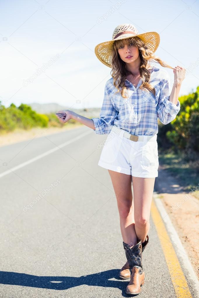 Trendy attractive blonde hitchhiking at the roadside