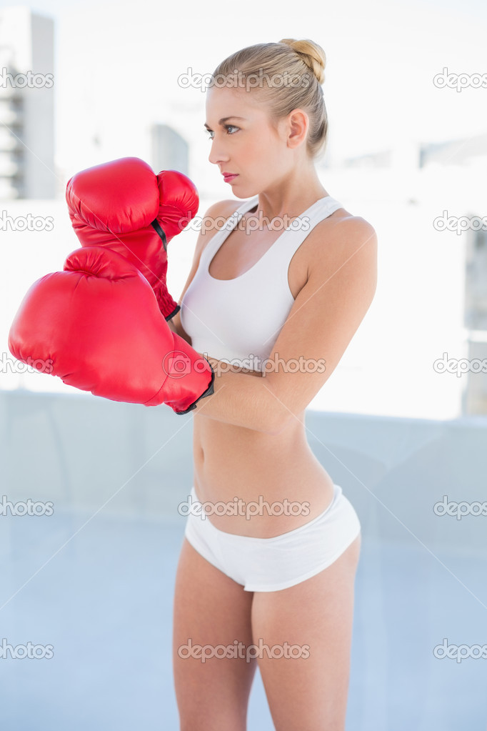 Concentrated young blonde model exercising with boxing gloves