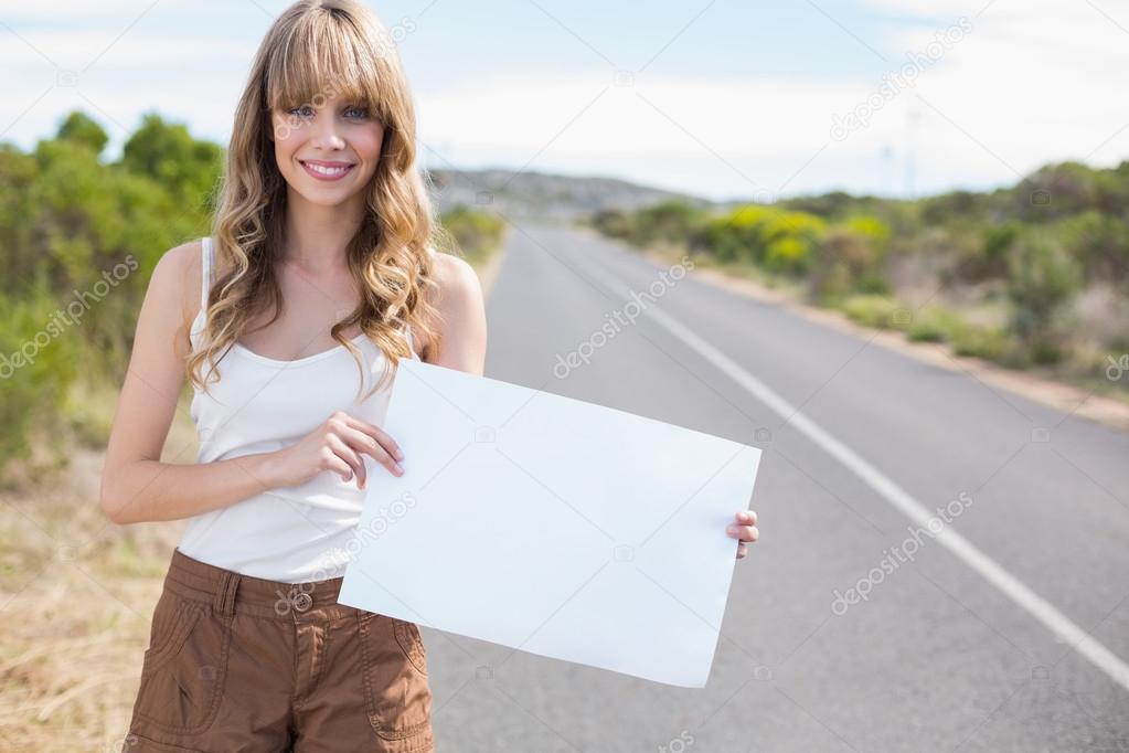 Smiling pretty woman holding sign while hitchhiking