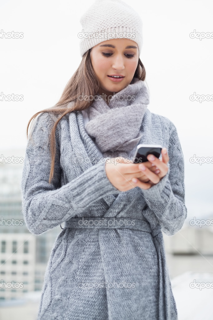 Focused woman with winter clothes on text messaging