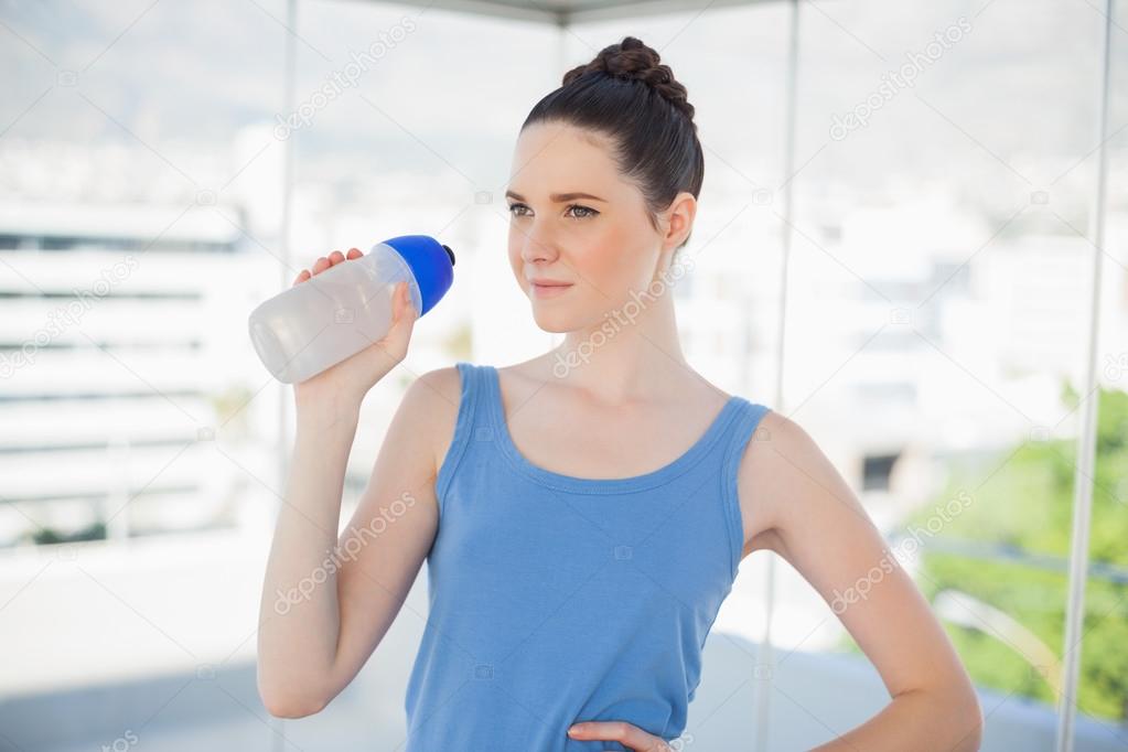 Pensive fit woman holding plastic flask