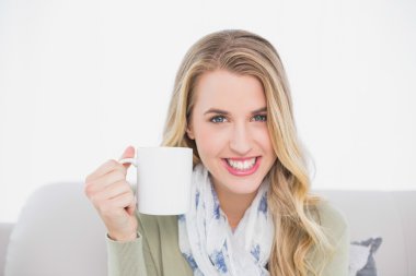 rahat bir koltukta oturup kahve fincan neşeli sevimli sarışın holding