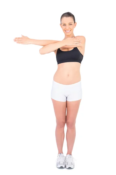 Mujer sonriente en ropa deportiva estiramiento mirando a la cámara — Foto de Stock