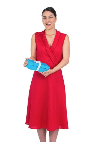Happy glamorous model in red dress holding present — Stock Photo, Image
