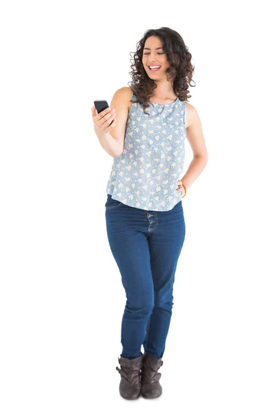 Cheerful attractive brunette looking at her smartphone — Stock Photo, Image