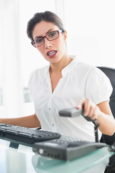 Beleidigte Geschäftsfrau, die am Schreibtisch sitzt und das Telefon auflegt — Stockfoto