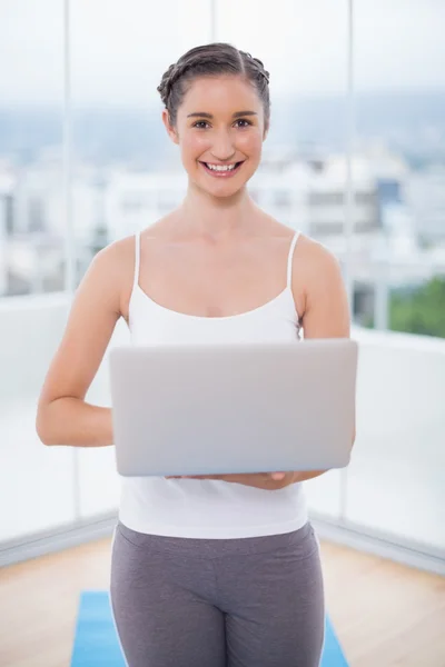 Fröhliche sportliche Brünette mit ihrem Laptop — Stockfoto