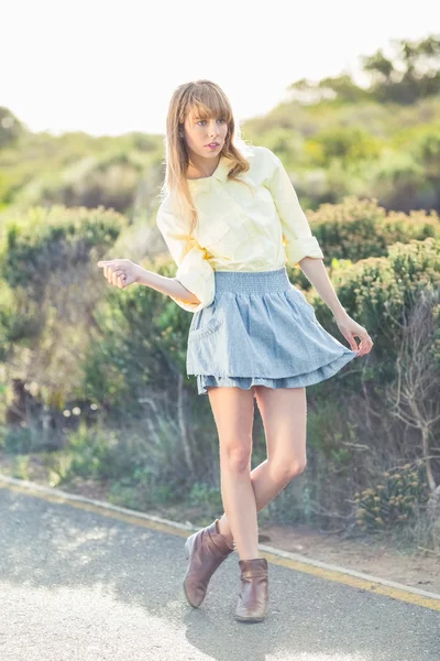 Gorgeous blonde woman hitchhiking on the roadside — Stock Photo, Image