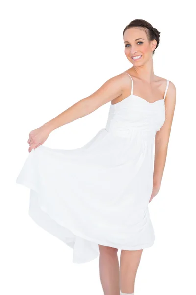 Веселая красивая молодая модель в белом платье танцует — стоковое фото