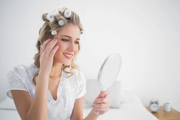 Happy blonde with hair curlers looking at reflection — Stock Photo, Image