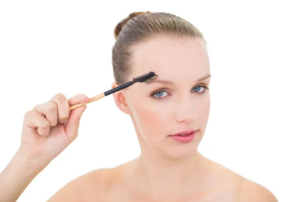 Natural pretty blonde model using an eyebrow brush — Stock Photo, Image