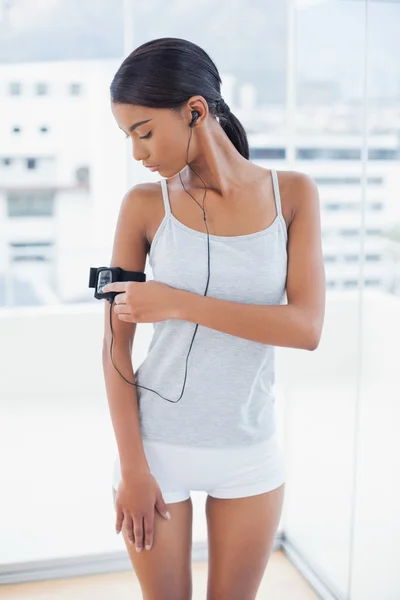 Pretty model in sportswear changing song on her mp3 — Stock Photo, Image