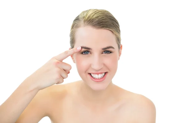 Smiling pretty blonde pointing at her eyebrow — Stock Photo, Image