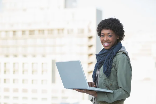 Smiling casual model holding her laptop — Stock Photo, Image