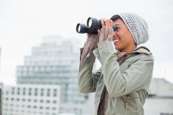 Lächelndes junges Model in Winterkleidung schaut mit Fernglas zu — Stockfoto