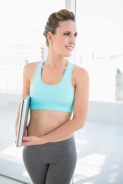 Mulher sorridente em sportswear segurando laptop — Fotografia de Stock