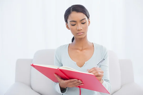 Ernsthafte attraktive Frau sitzt auf gemütlichem Sofa und schreibt — Stockfoto