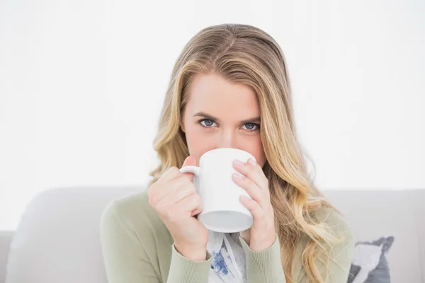 Söt blondin dricker kaffe sitter på mysiga soffa — Stockfoto