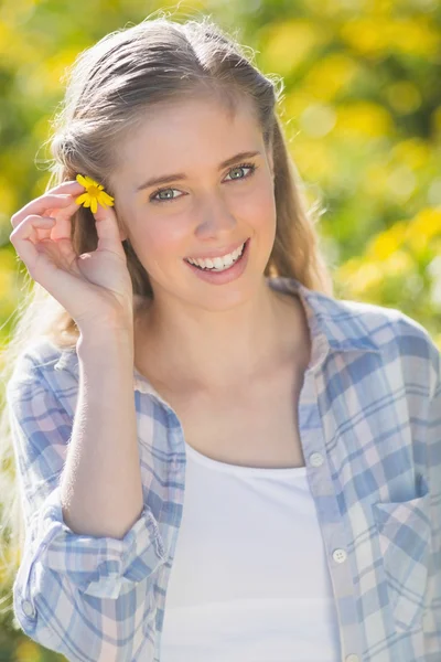 Mujer rubia poniendo flor en el pelo — Foto de Stock