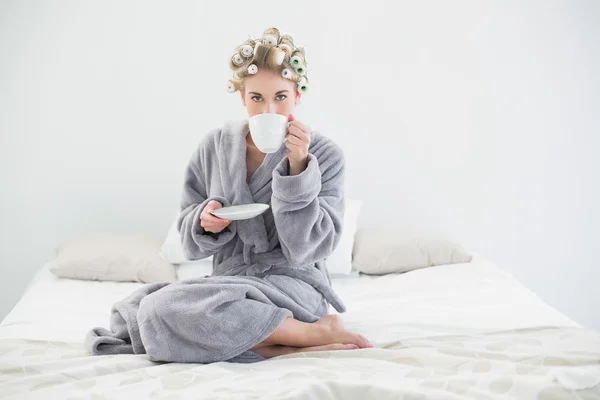 Attraktive, entspannte blonde Frau in Lockenwicklern, die Kaffee trinken — Stockfoto